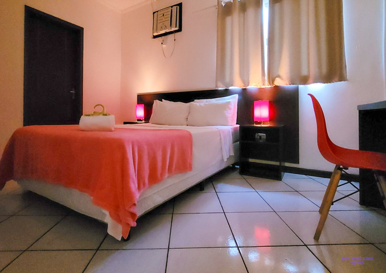A double bed with a coral throw and red bedside lamps in a room at the Paraty accommodation