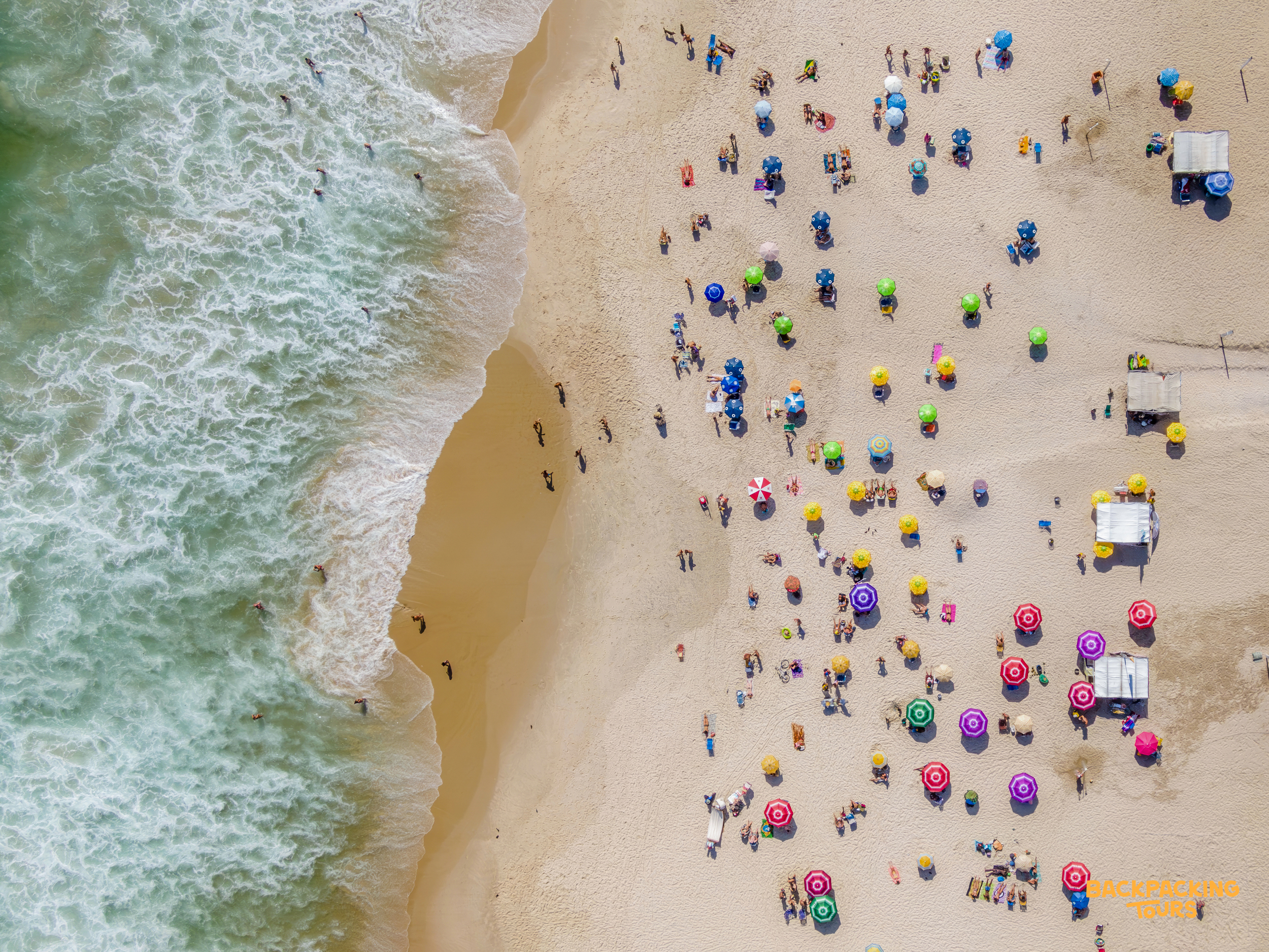 An aerial view of Copacabana Beach in Rio de Janeiro, bustling with colorful umbrellas and sunbathers.