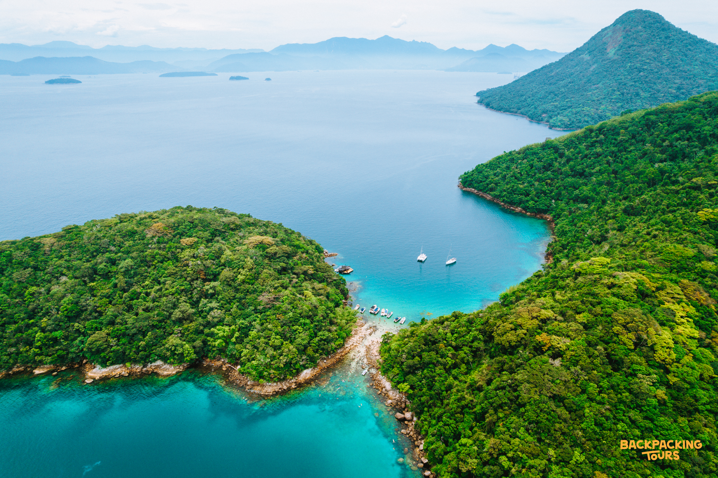 Stunning turquoise waters and lush green islands of Ilha Grande, Brazil, with boats in calm bays.
