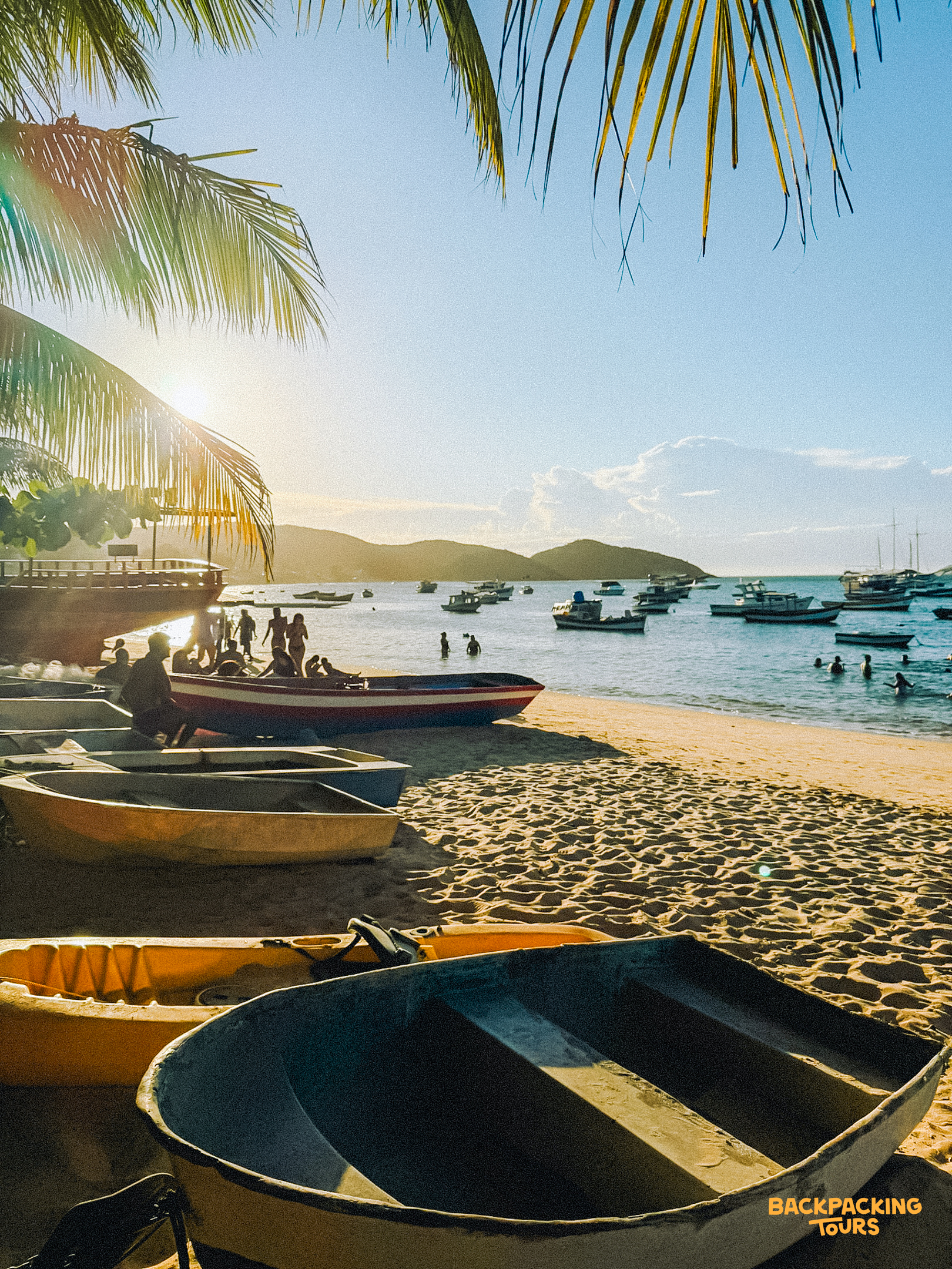 Tropical beach on Ilha Grande with boats pulled ashore and people swimming in the calm bay.