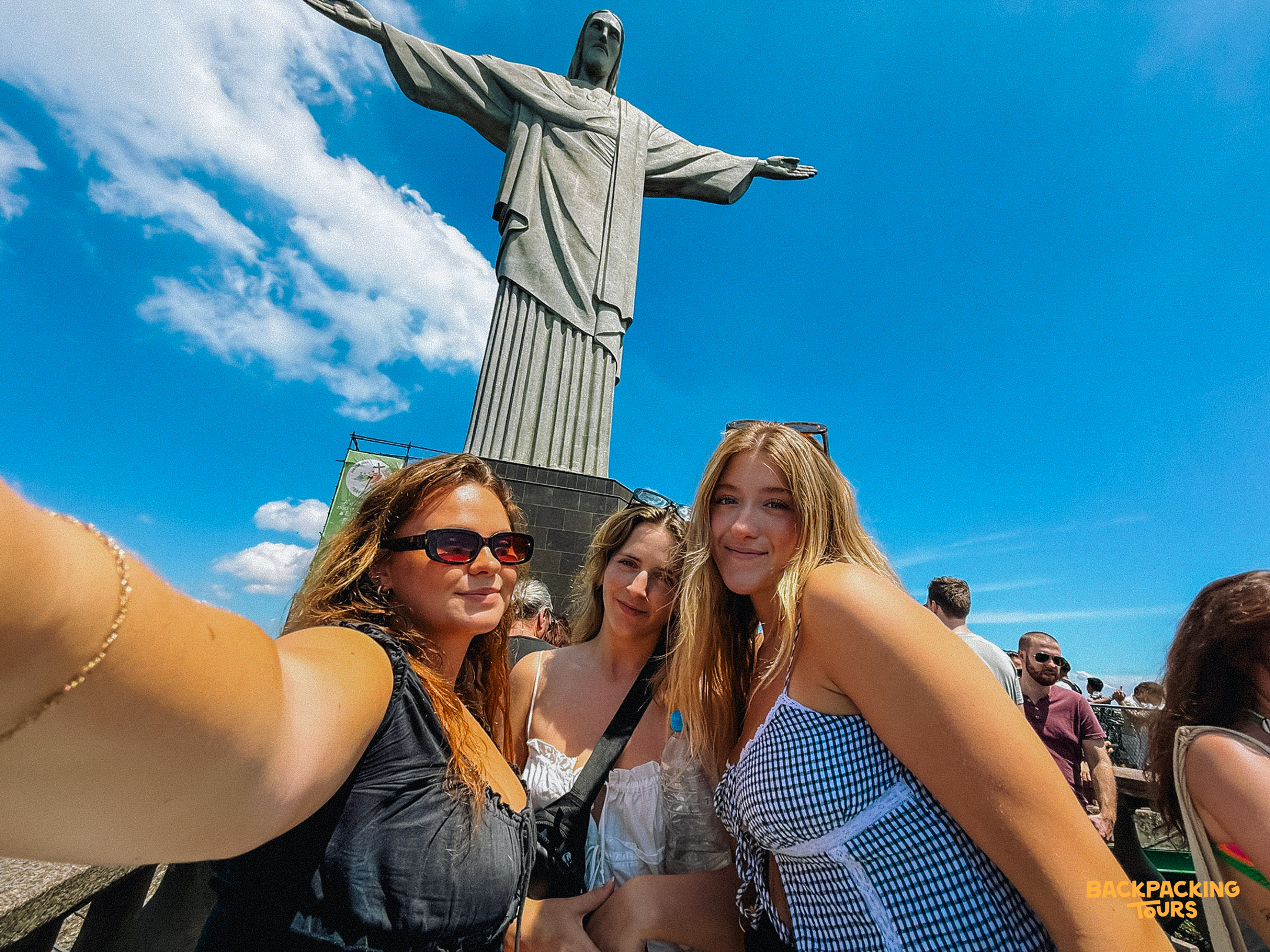Three happy women take a selfie with the iconic Christ the Redeemer statue in Rio de Janeiro.