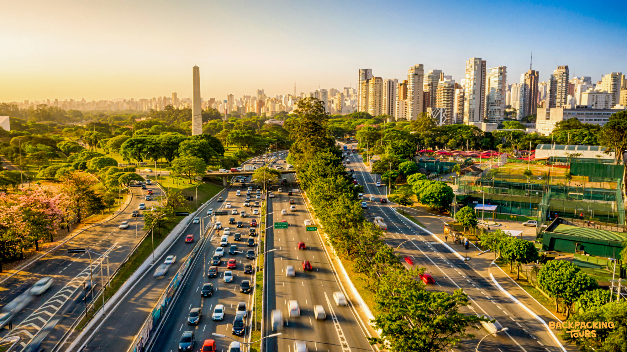 An expansive view of a busy São Paulo highway with city buildings and an obelisk.