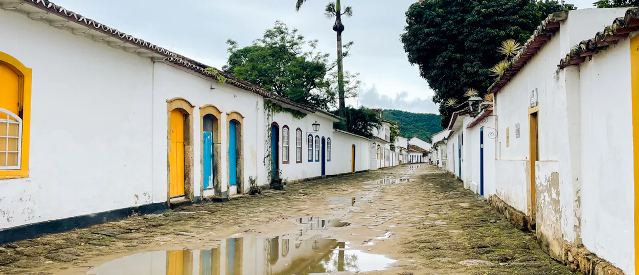 Colonial buildings with bright yellow and blue doors line a wet cobbled street in Paraty.