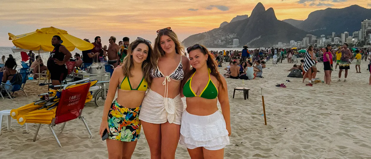 Three happy women pose on a crowded Copacabana Beach at sunset in Rio de Janeiro.