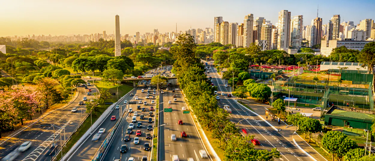 São Paulo city panorama with busy highways, green parks, a prominent obelisk, and a towering skyline.