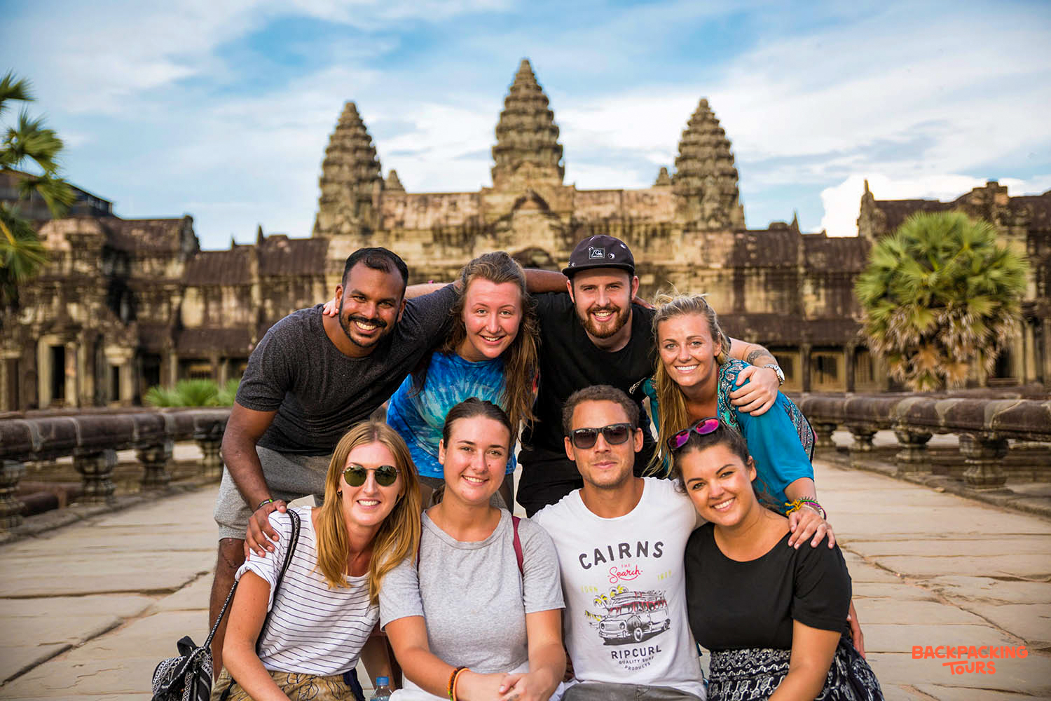 Happy backpackers pose for a group photo in front of the ancient Angkor Wat temple.