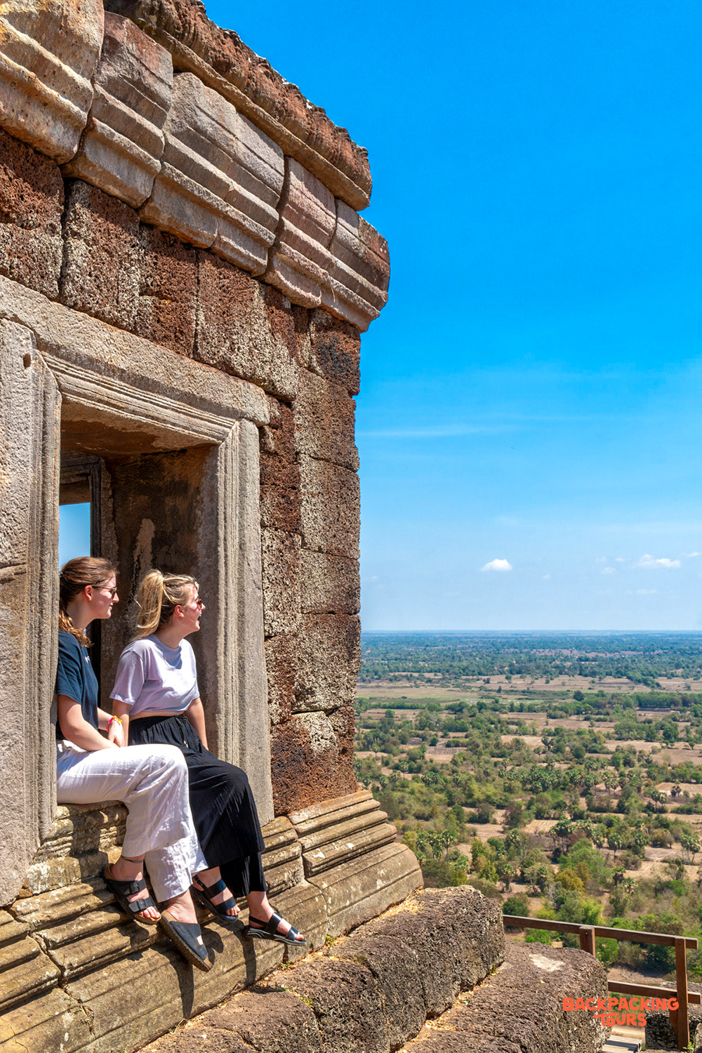 Two friends enjoy a panoramic view from an ancient temple window in Siem Reap.