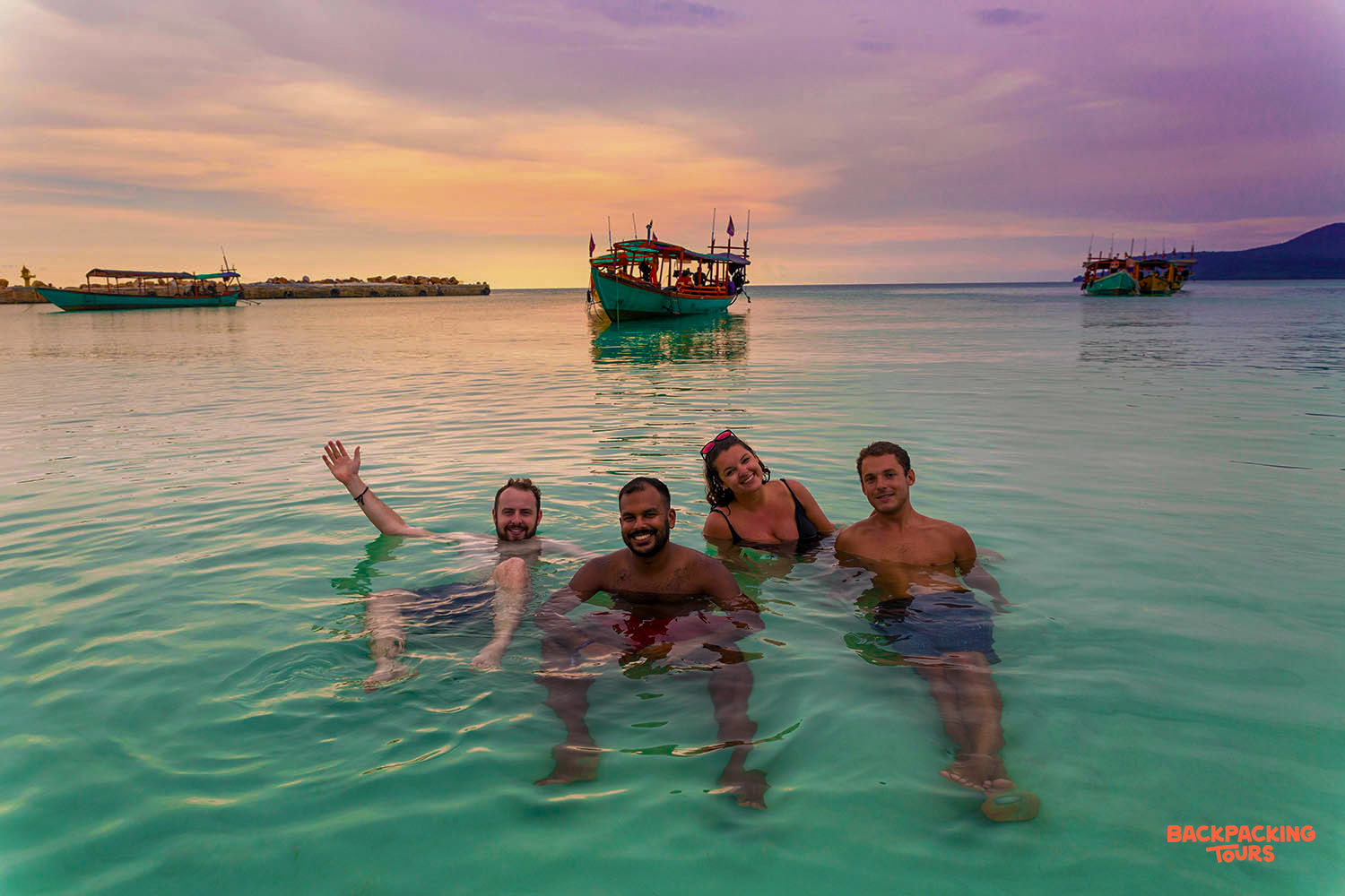 Four happy backpackers enjoy a refreshing sunset swim in the clear turquoise waters of Koh Rong.