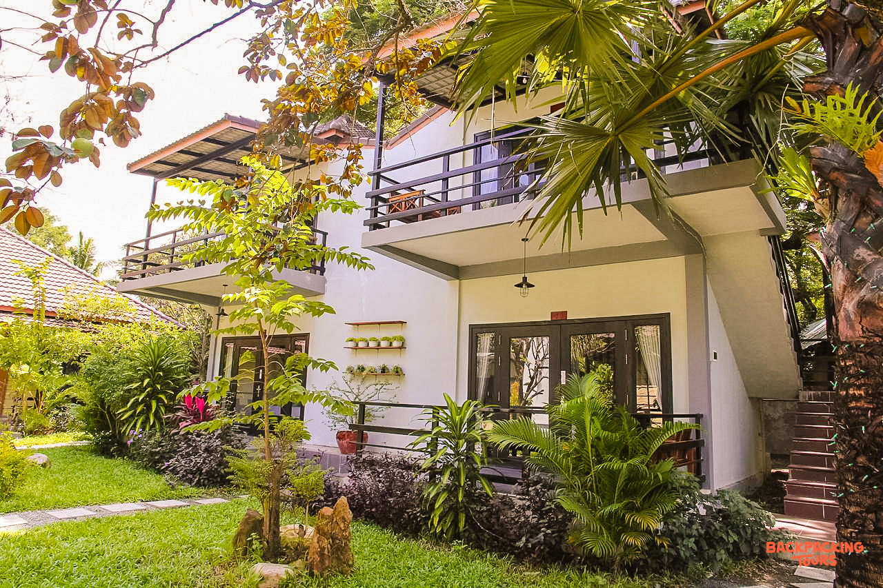 A comfortable two-story guesthouse with balconies, nestled among lush tropical gardens in Kampot.
