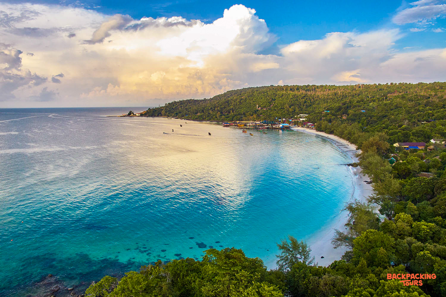 Beautiful Koh Rong bay with clear turquoise water, a white sand beach, and lush green hills.