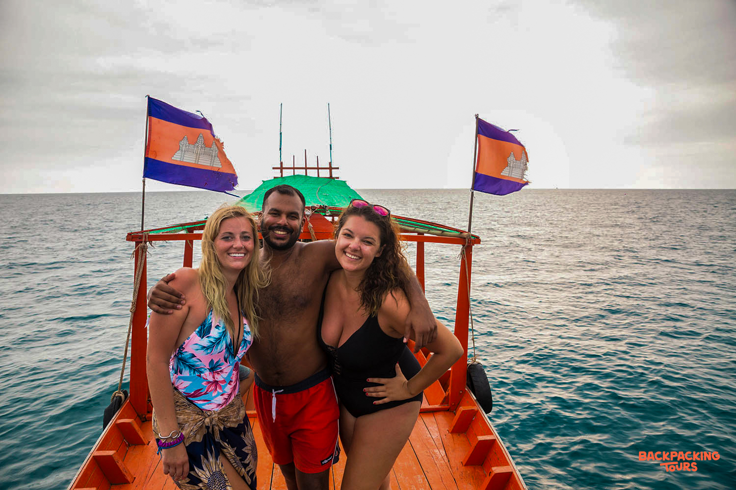 Three happy backpackers smiling on a private longtail boat trip in Koh Rong, Cambodia.