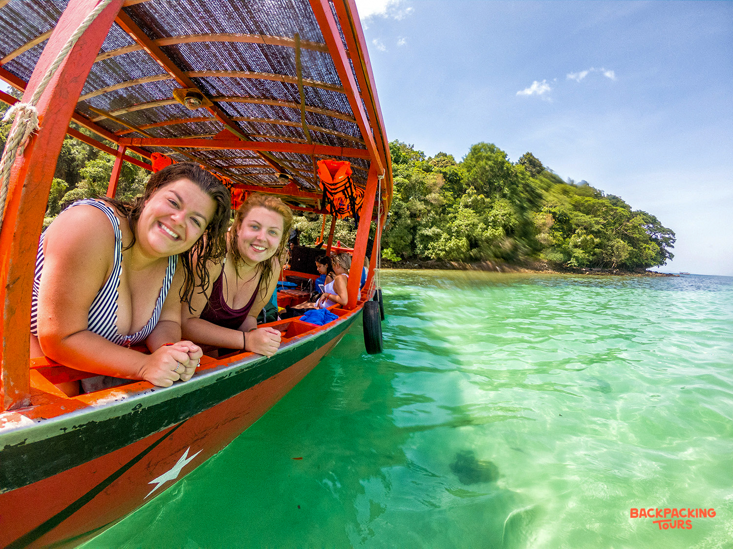 Smiling women enjoy a private longtail boat trip in the clear waters of Koh Rong.