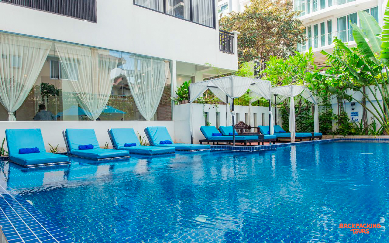 A beautiful hotel swimming pool in Phnom Penh with blue lounge chairs and white cabanas.