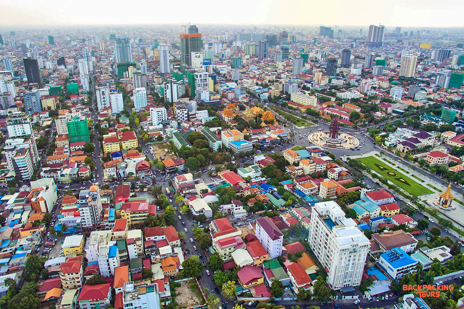 An expansive aerial view of Phnom Penh's bustling cityscape, featuring dense buildings and a central monument.