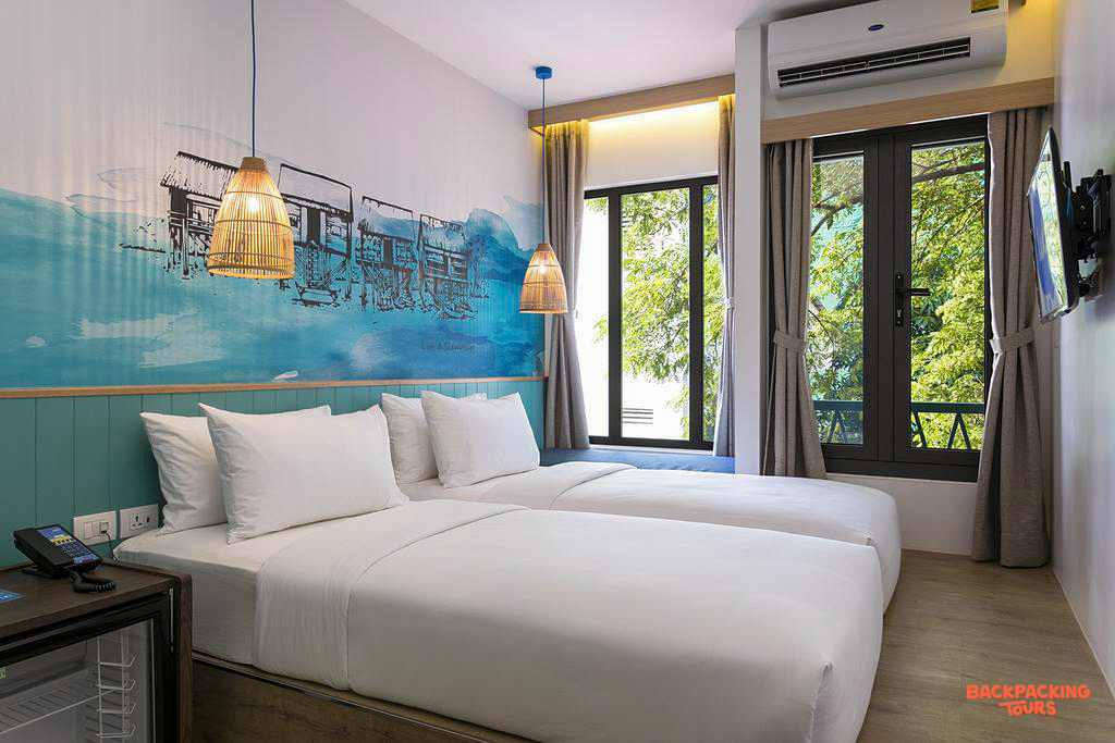 A bright and modern twin room in Siem Reap with comfortable beds and a unique water village mural.