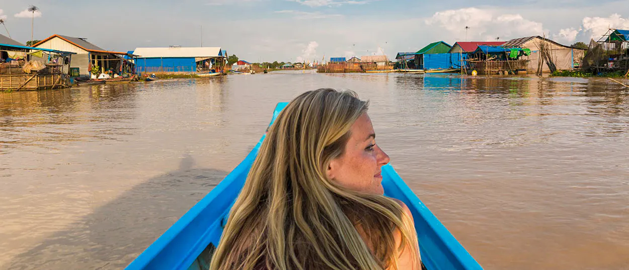 A woman cruises through a peaceful floating village in Siem Reap, Cambodia, on a sunny day.