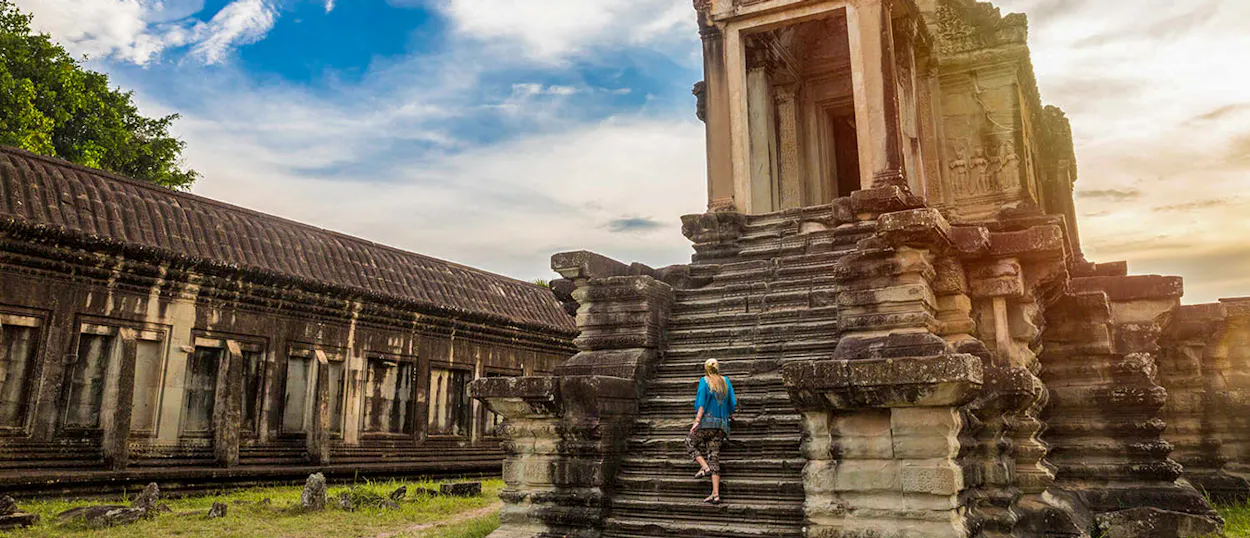 A traveler climbs the weathered stone steps of the magnificent Angkor Wat temple in Cambodia.