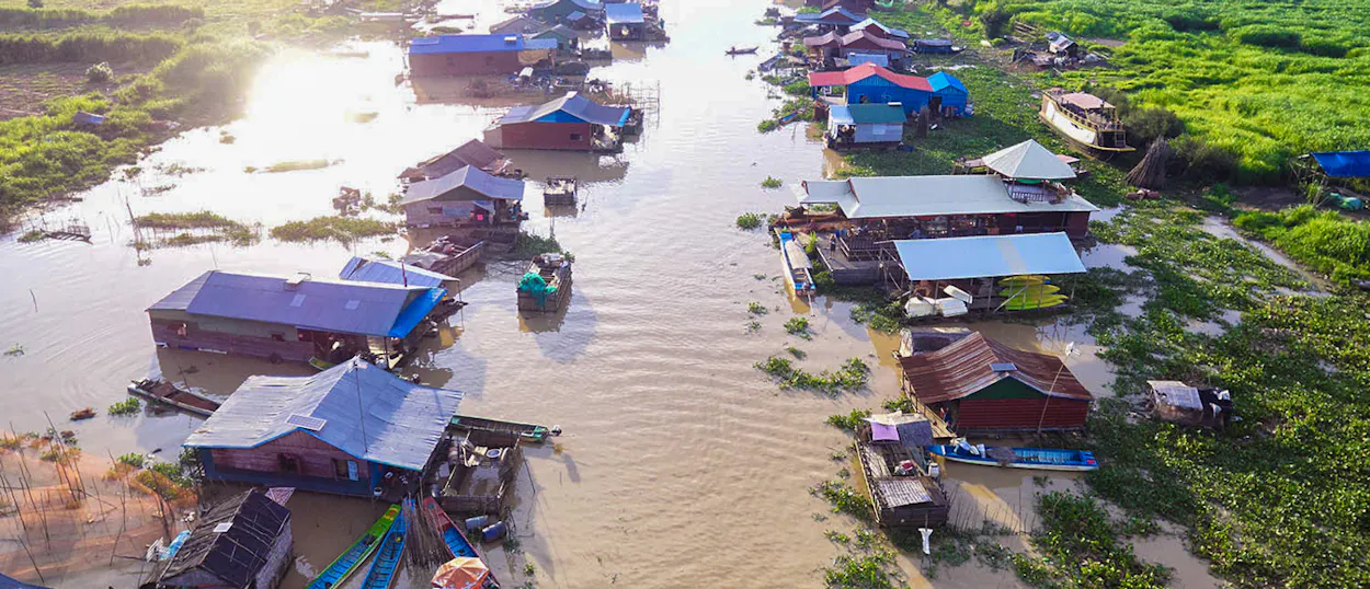 Aerial view of a peaceful floating village with houses lining a waterway in Siem Reap, Cambodia.