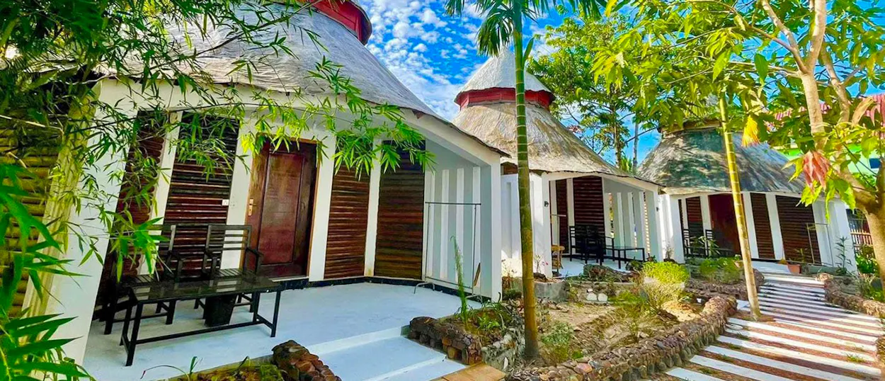 Thatched-roof bungalows with white walls and dark shutters at a tropical resort on Koh Rong Sanloem.