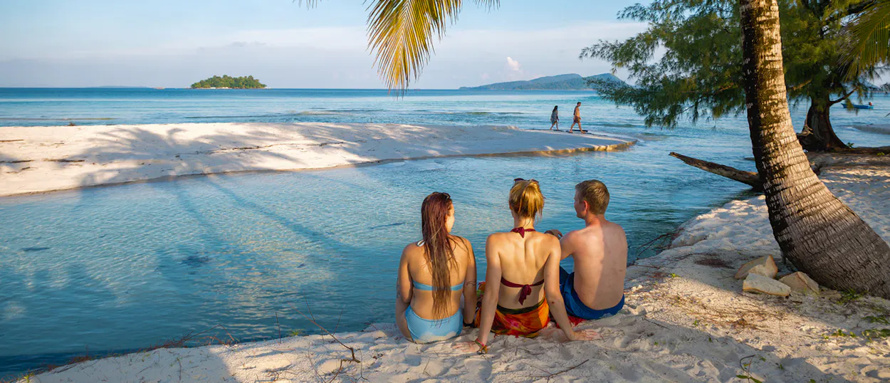 Friends relax on a pristine white sand beach, enjoying the clear turquoise waters of Koh Rong.