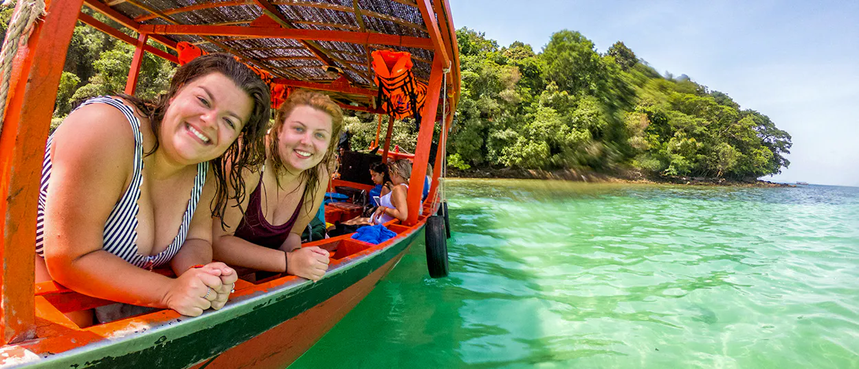 Smiling women on a longtail boat exploring the beautiful clear waters of Koh Rong, Cambodia.