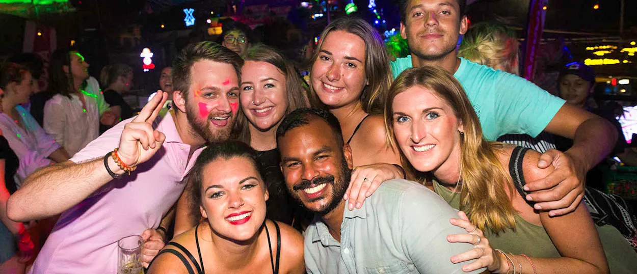 A joyful group of young backpackers smiling and posing together during a lively night out in Siem Reap.
