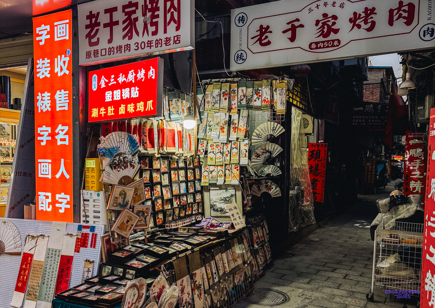 Colourful stalls line a bustling evening market street in Xi'an, offering various souvenirs.