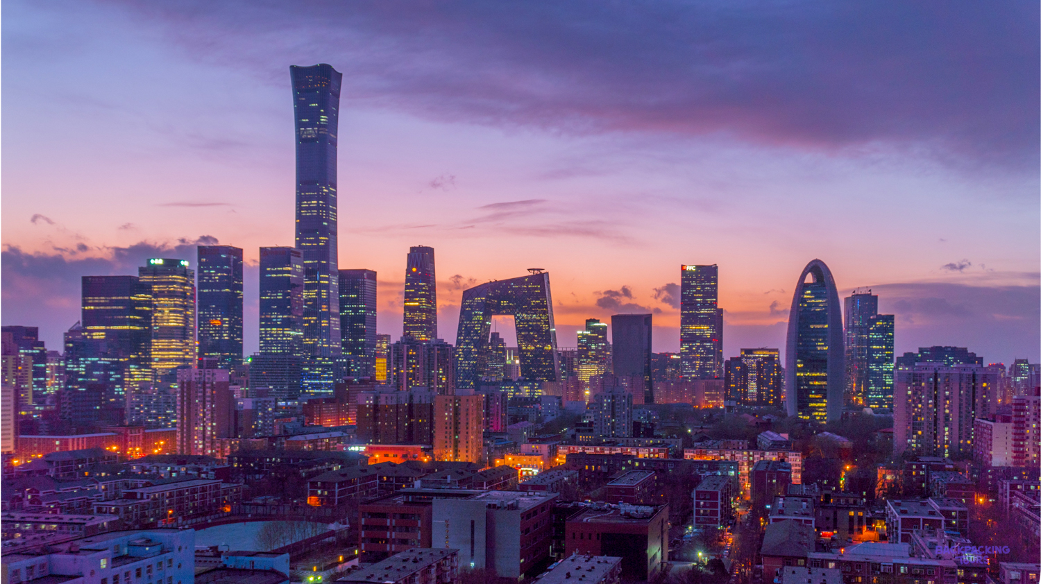 Beijing's impressive skyline glows at twilight, with illuminated skyscrapers under a beautiful purple sky.