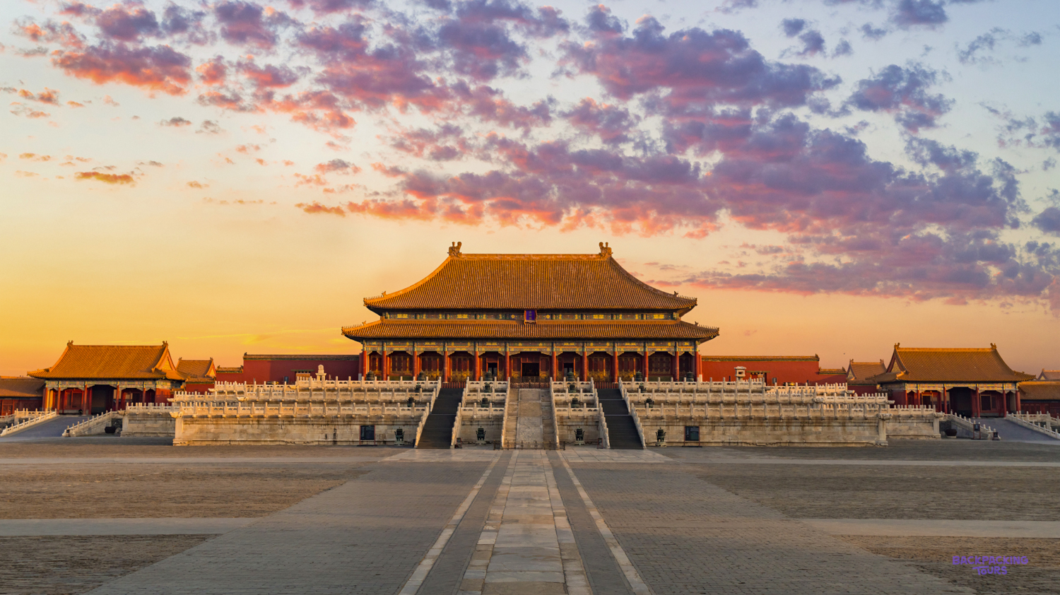 The magnificent Forbidden City palace in Beijing glows under a dramatic, colorful sunset sky.