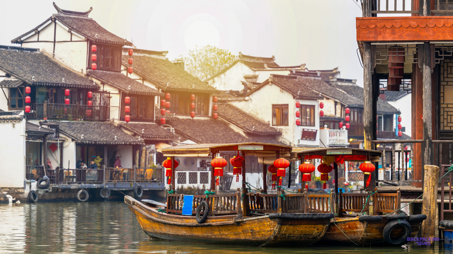 Traditional Chinese buildings with red lanterns and wooden boats on a canal in old Shanghai.