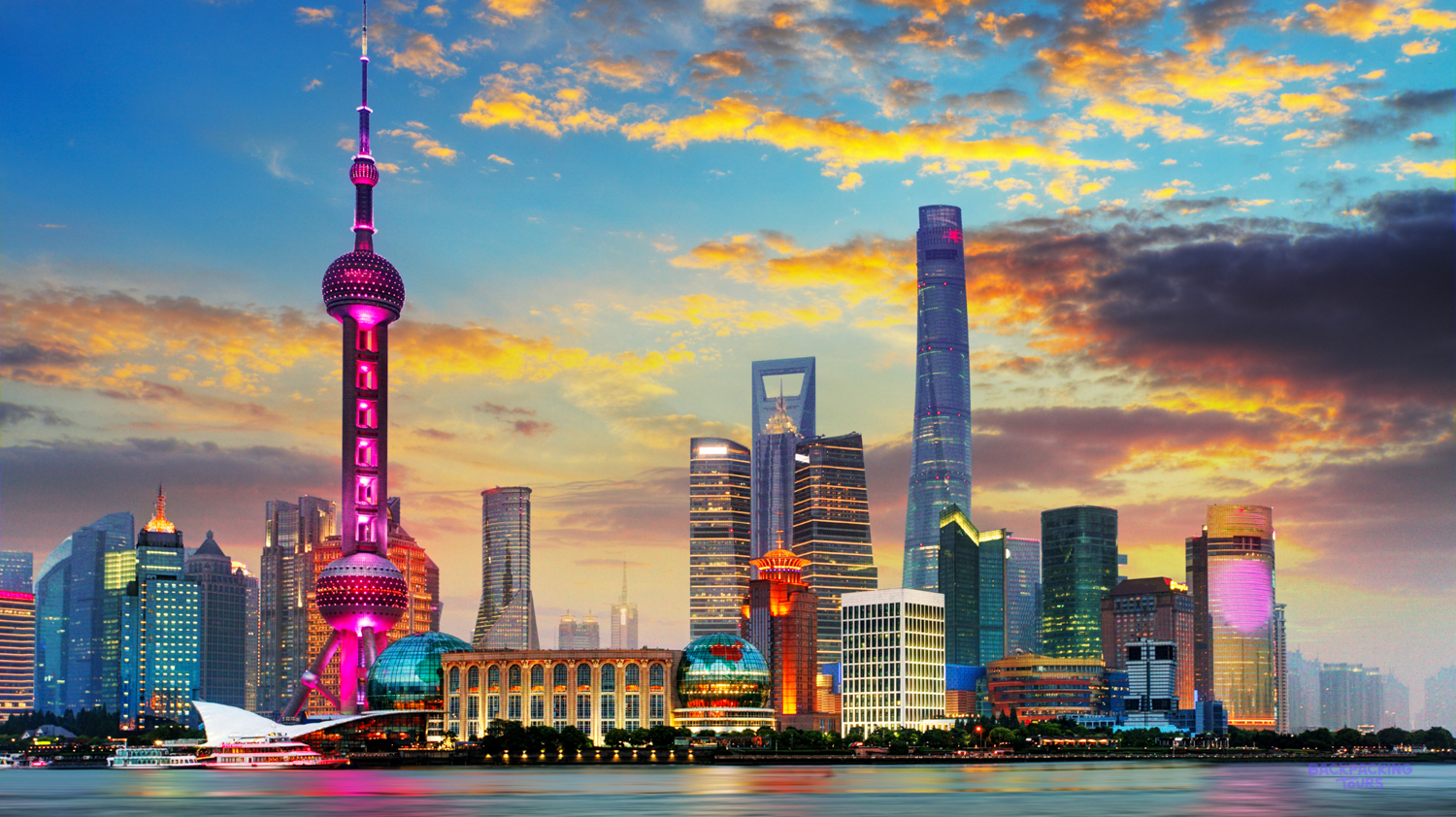 Shanghai's iconic skyline glows at sunset, with the Oriental Pearl Tower prominent by the river.
