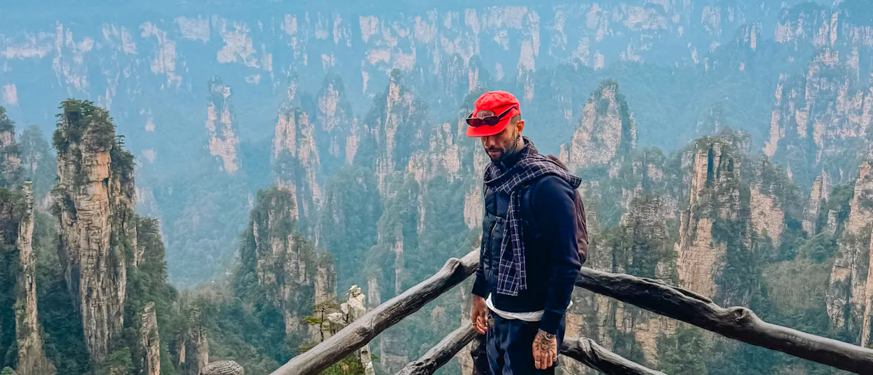 Traveler in a red cap admires the breathtaking, mist-covered Avatar Mountains in Zhangjiajie, China.