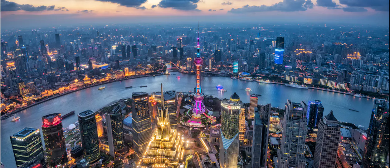 Shanghai's dazzling city lights illuminate the Huangpu River and iconic skyscrapers at twilight.