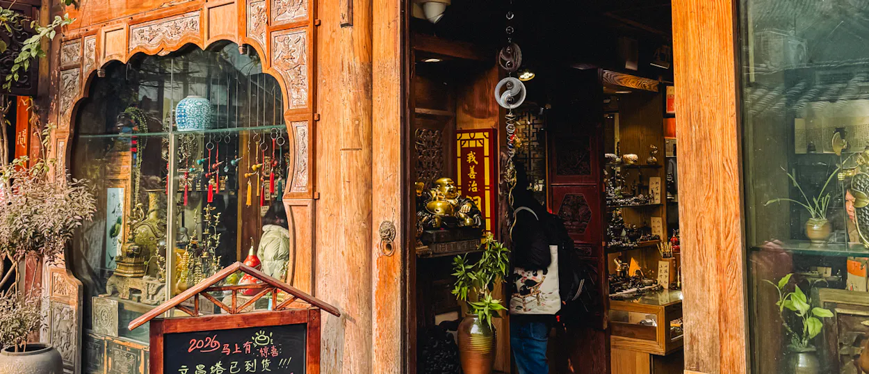 A person with a backpack stands at the entrance of a traditional shop in Chengdu's Kuanzhai Alley.