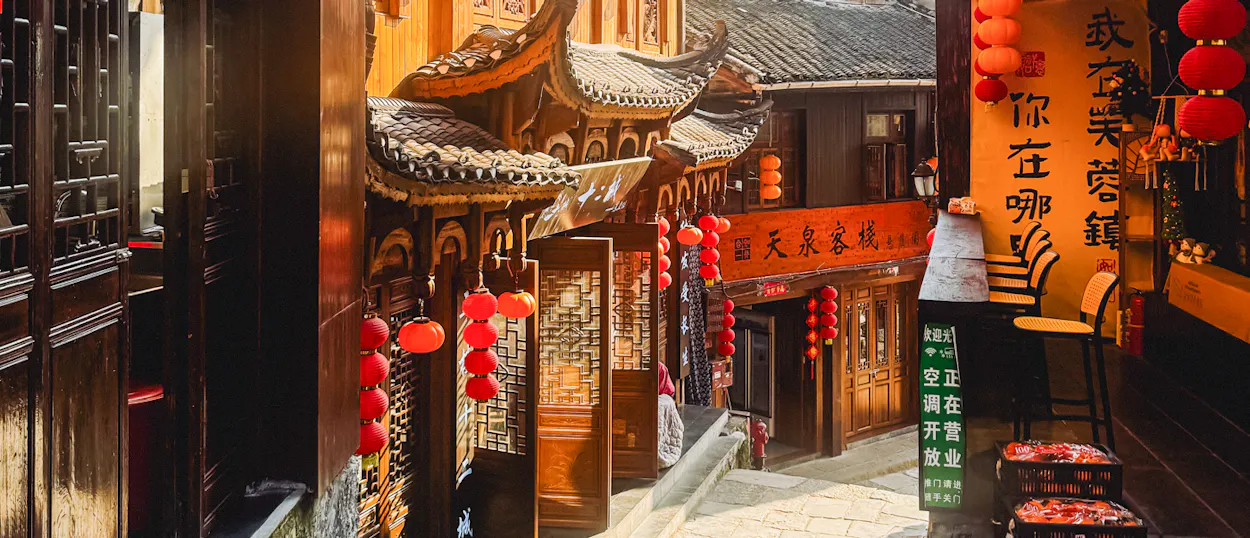 Traditional Chinese buildings line a narrow street adorned with many red lanterns in Furong Ancient Town.