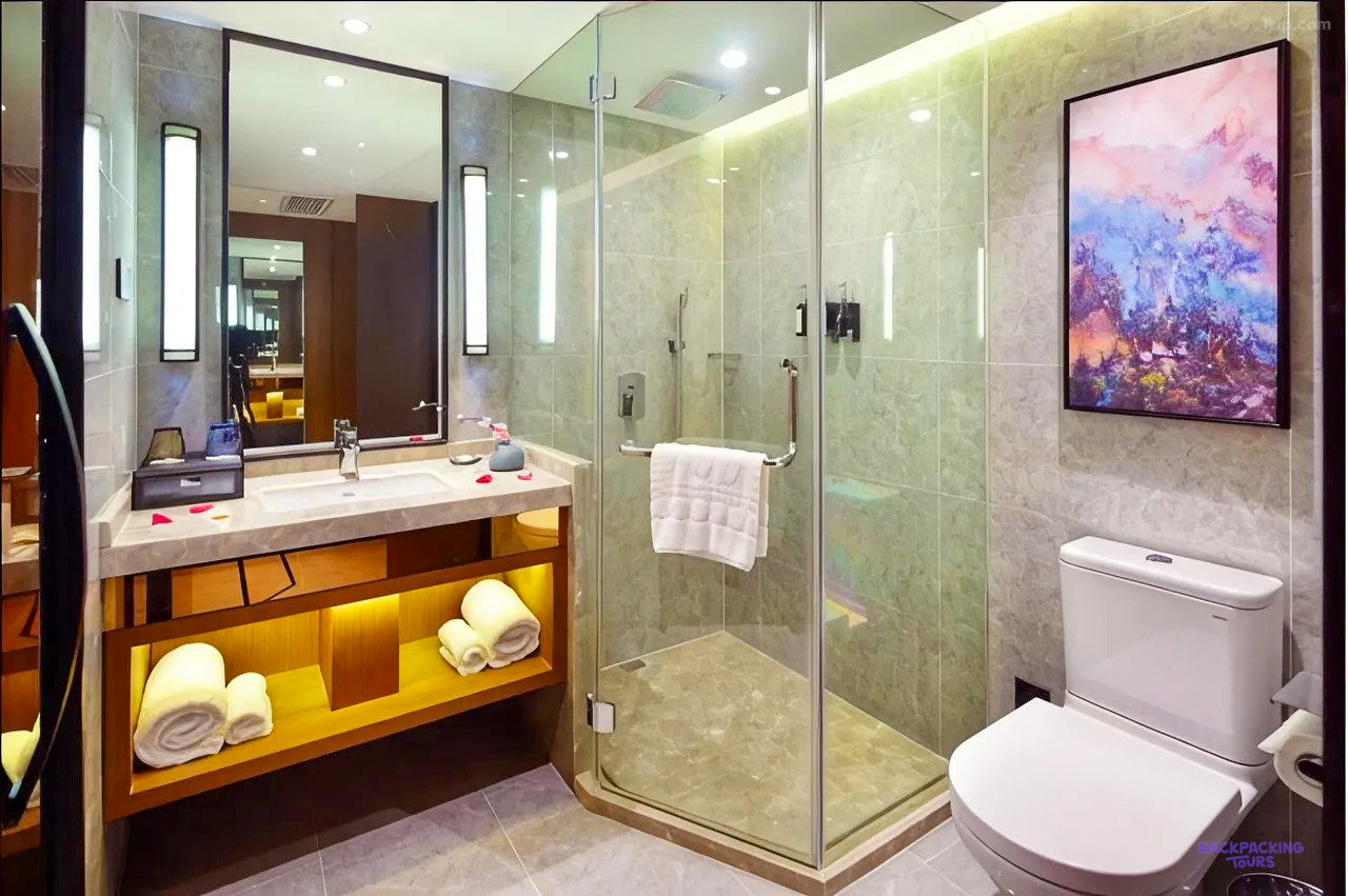 The bathroom at the hotel in Shanghai, with a glass shower and a painting on the wall