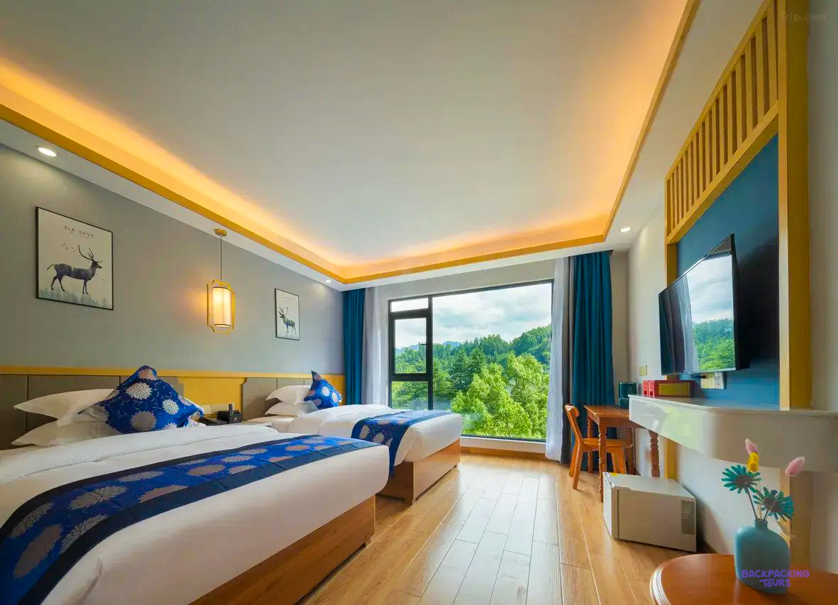 A room with blue bedding and a big window onto the trees at the hotel in Zhangjiajie