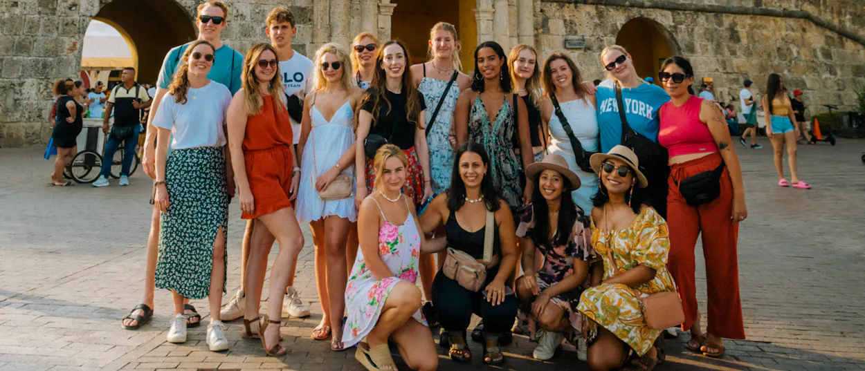 Happy young travelers posing together in front of historic stone arches during a Cartagena walking tour.