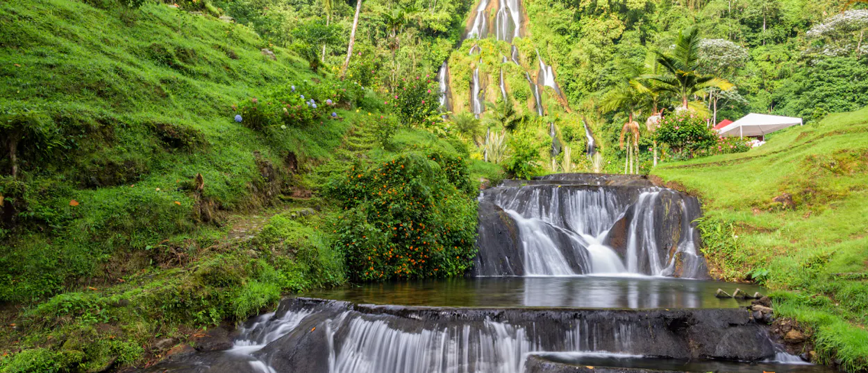 Lush green jungle surrounds cascading waterfalls and natural pools in Santa Rosa de Cabal.