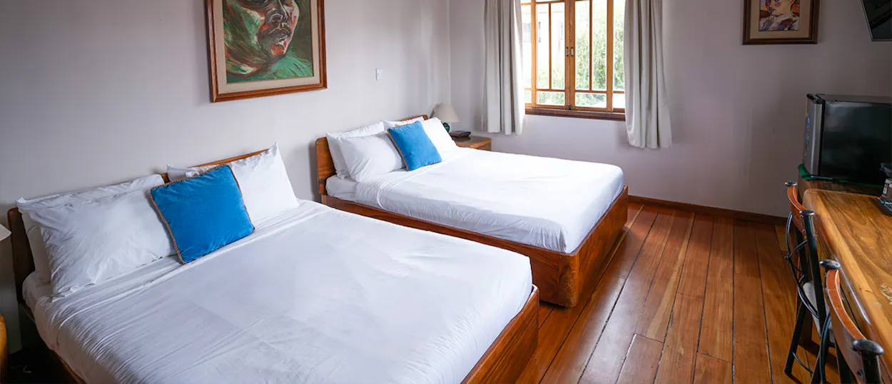 A clean hotel room in San José, Costa Rica, with two beds, wooden floors, and a window.