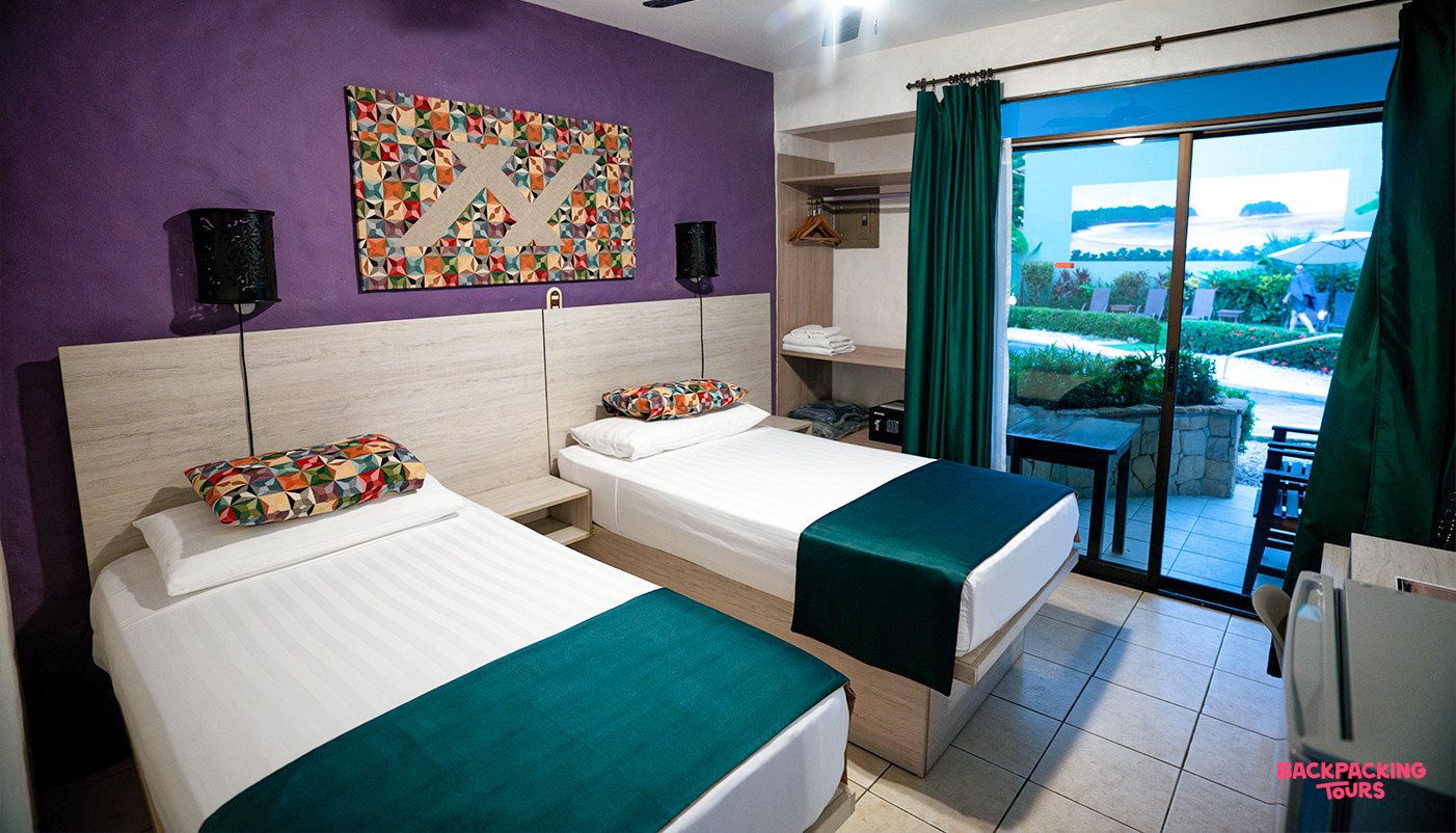 Inviting twin beds in a colorful Samara hotel room, with a view of the tropical outdoor area.