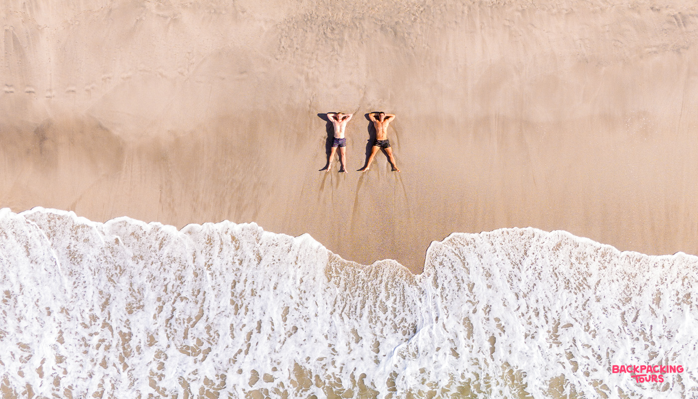 Two friends relaxing on a beautiful sandy beach with foamy waves in Guanacaste, Costa Rica.