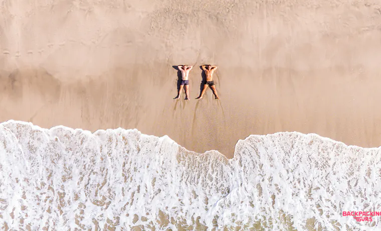 Two friends relaxing on a beautiful sandy beach with foamy waves in Guanacaste, Costa Rica.