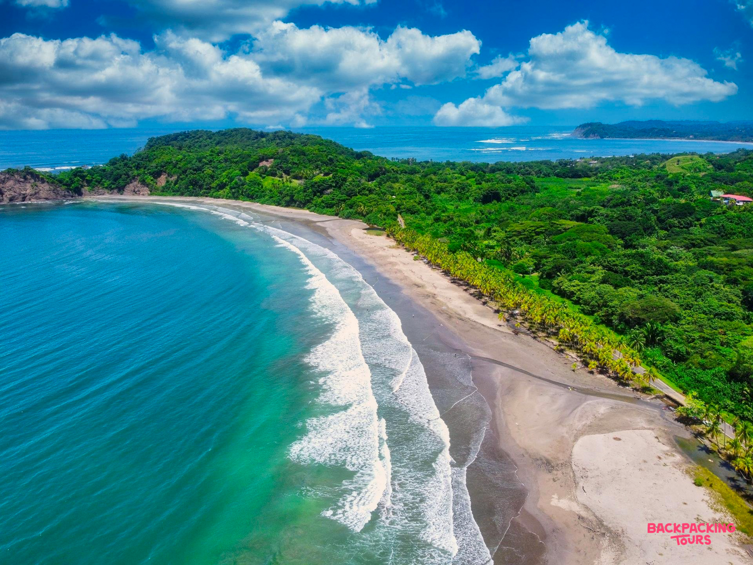 A pristine Costa Rican beach with clear turquoise water, gentle waves, and lush green jungle.
