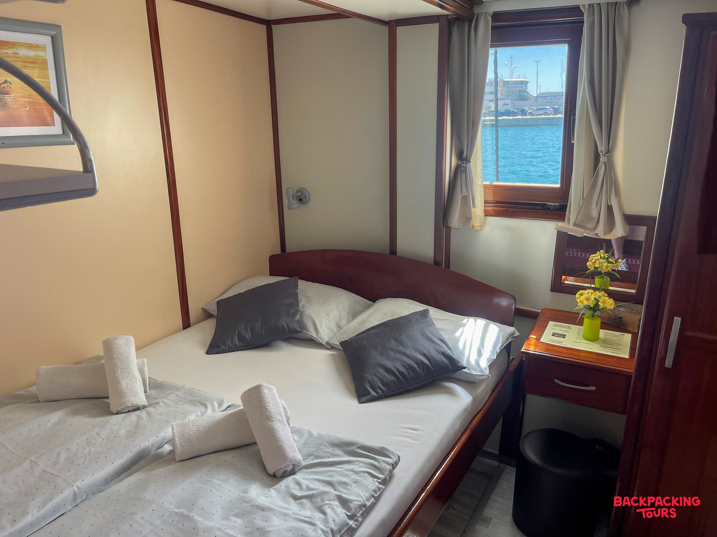 A comfortable double cabin on a premium sailing boat, with a window overlooking the blue sea.