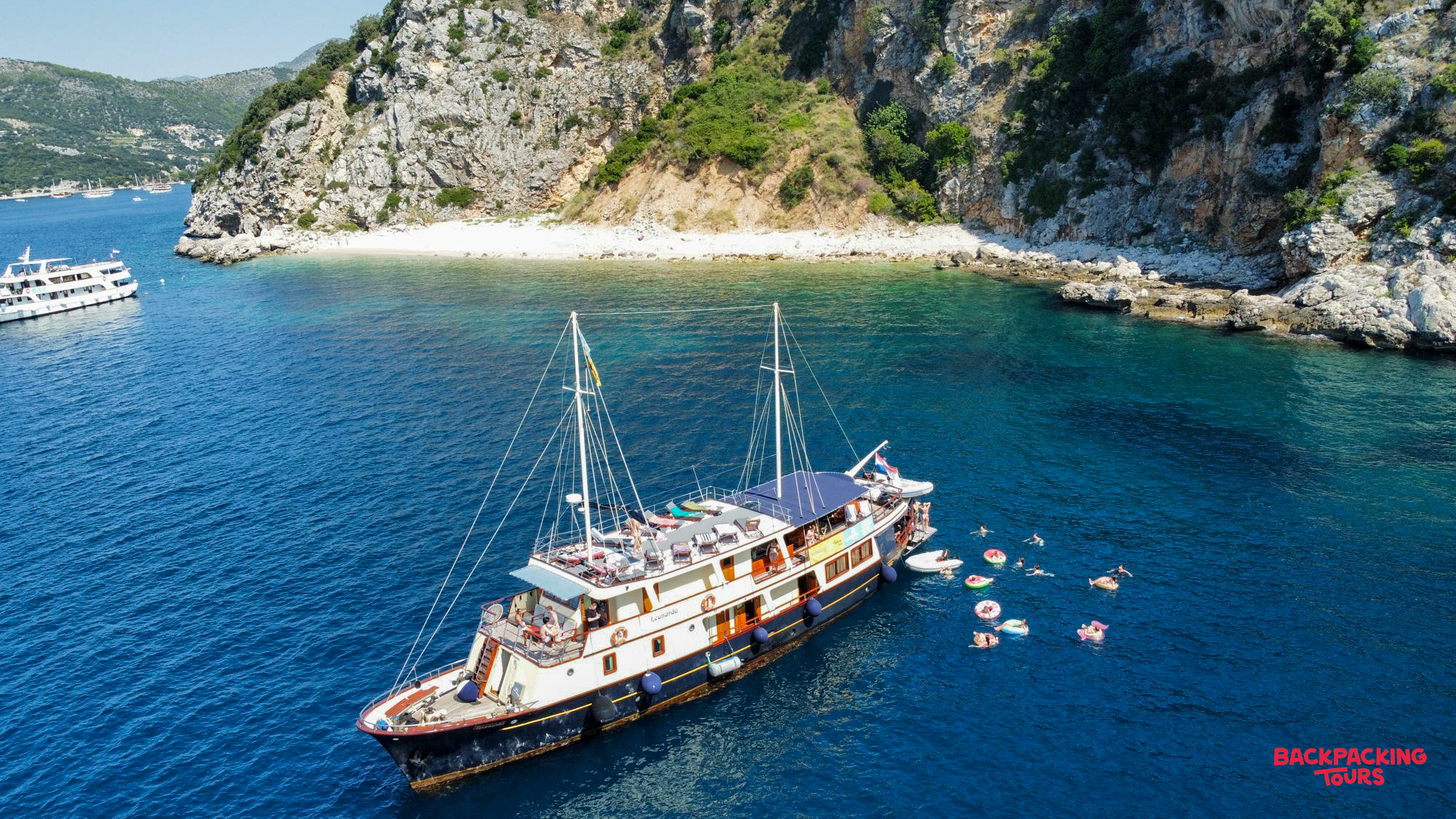 Guests enjoy a swim stop from their sailing boat in a beautiful, clear blue Croatian bay.
