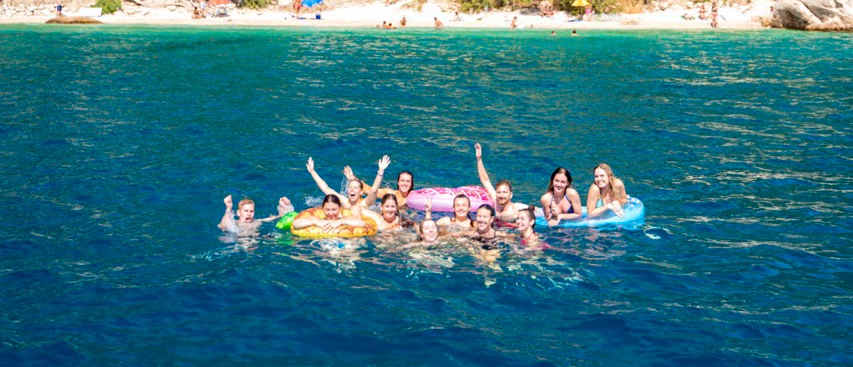 A joyful group of friends swimming and relaxing in the clear blue waters of Makarska, Croatia.