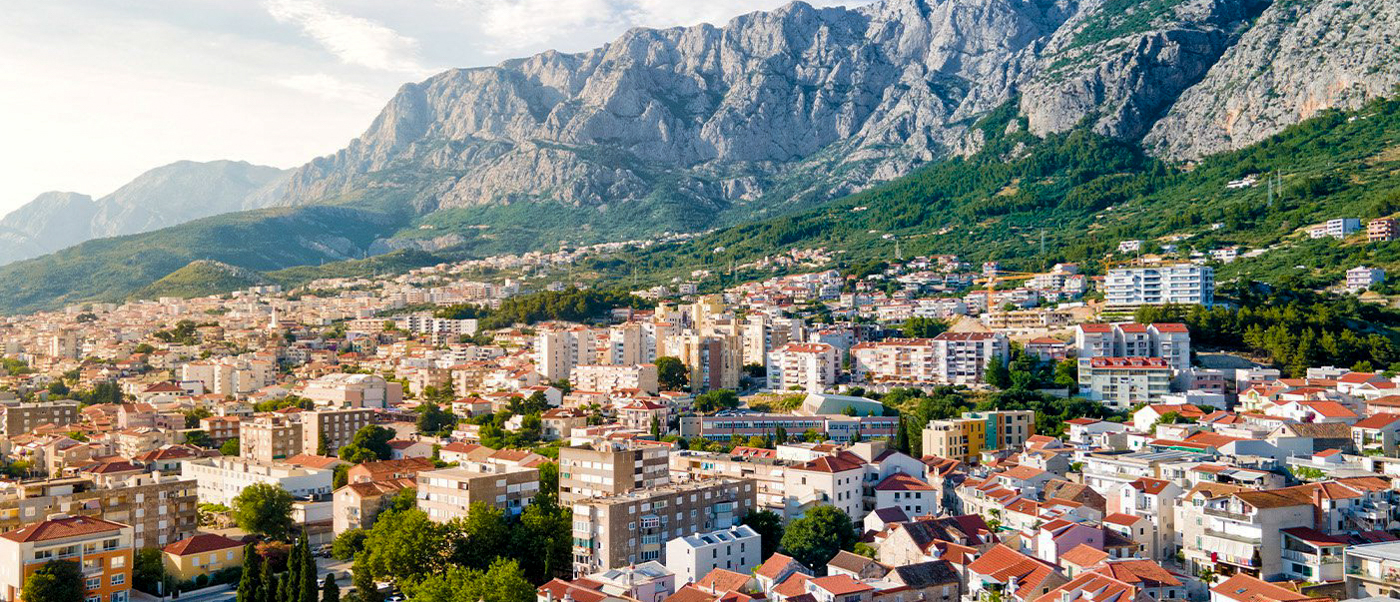 Makarska town in Croatia, with numerous buildings and red roofs, nestled against dramatic mountains.