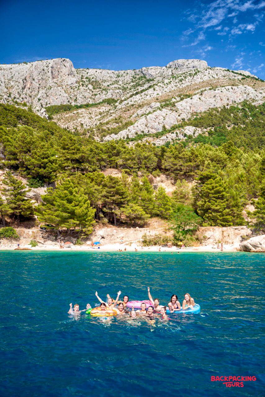 Smiling travelers enjoy a swim stop in the beautiful blue waters of Makarska, Croatia.