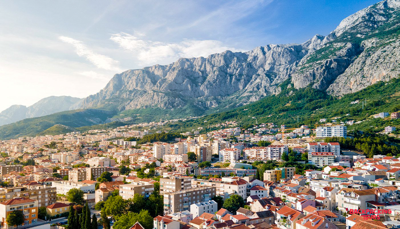 Makarska town in Croatia, with red-roofed buildings at the base of the dramatic Biokovo mountains.